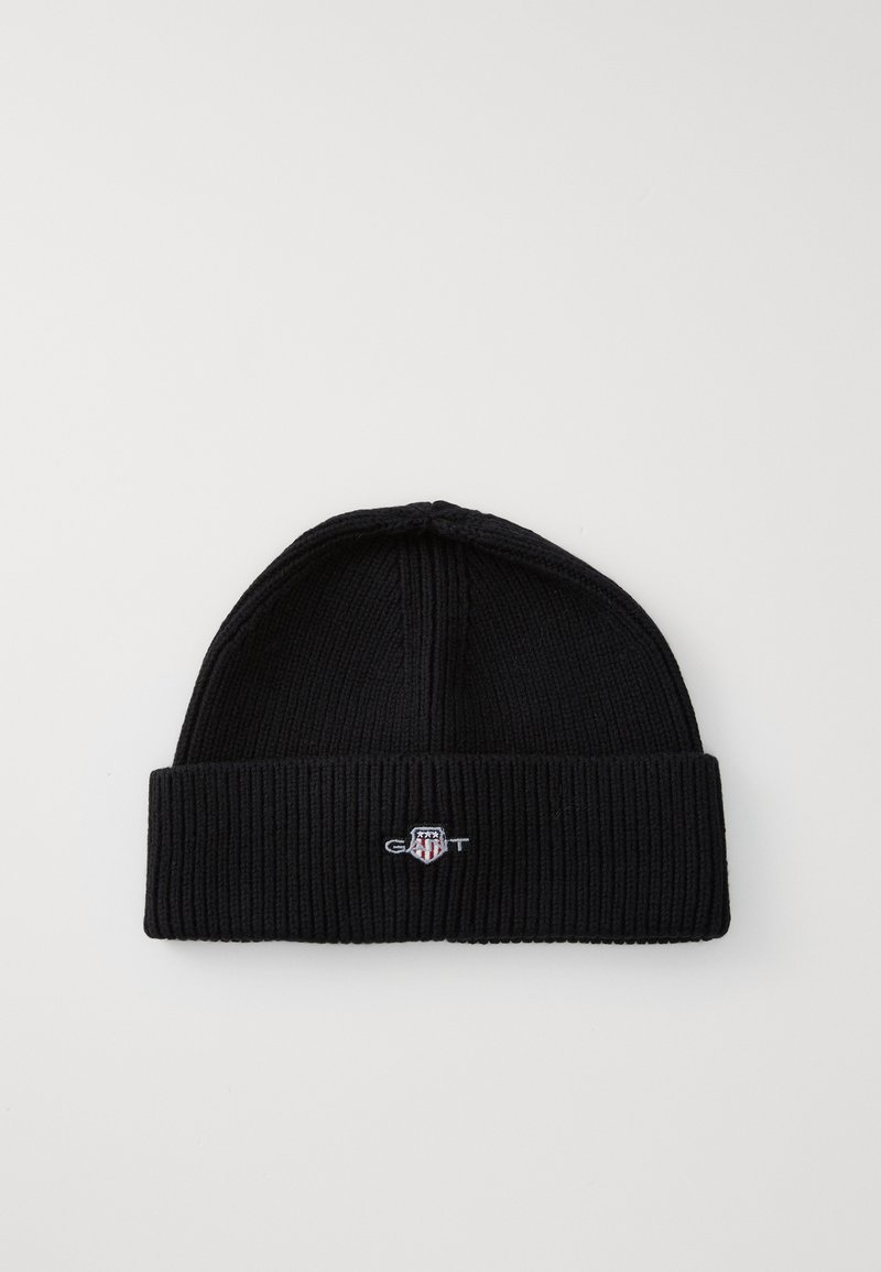 Bonnet en tricot noir avec une texture côtelée et un revers replié, comportant un petit logo brodé en blanc, rouge et bleu.