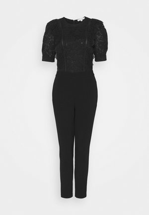 Combinaison noire avec manches courtes en dentelle bouffantes, corsage en dentelle florale, taille ajustée et pantalon droit.