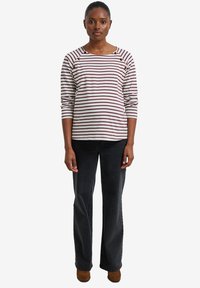 Gestreiftes Langarmshirt mit weinroten und weißen Streifen, runder Ausschnitt und Knopfdetails. Kombiniert mit dunklen Schlagjeans und braunen Schuhen.