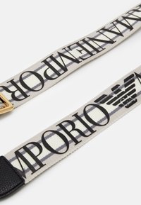 Cintura in tessuto con motivo ripetuto in nero su sfondo crema con strisce grigie; hardware in metallo color oro a un'estremità.