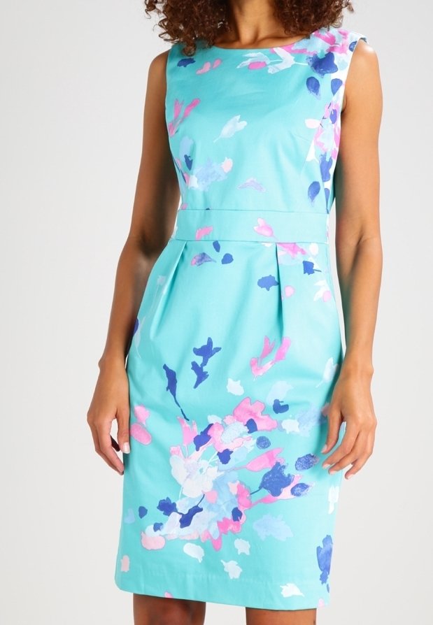 Une robe ajustée en tissu bleu sarcelle avec un motif floral rose, bleu et blanc. Elle présente un col arrondi et des plis à la taille.