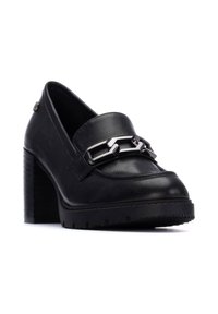 Mocasines de tacón alto de cuero negro con un detalle de cadena plateada en la parte delantera y suela de goma texturizada para mayor tracción.