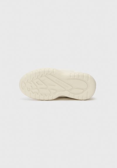 Heledad beež sneaker'i tald, millel on tekstuuriga kumm, lainekujuline tallamuster ja brändingu elemendid külgedel. Siledad servad ja ümarad nurgad.