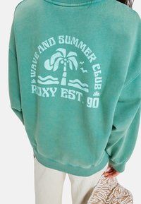 Zielona, oversize'owa bluza z białym graficznym wzorem palm i fal, z napisem "Wave and Summer Club Roxy EST. 90".