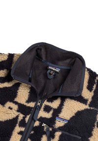 Giacca in pile con un motivo nero e beige, colletto alto, chiusura con zip e logo Patagonia sul petto. Texture morbida con colori a contrasto.