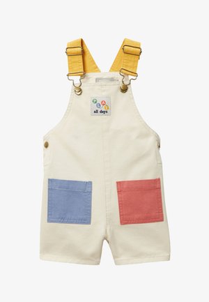 Salopette short crème pour tout-petit avec bretelles jaunes réglables, poches avant bleues et rouges, et un écusson "PLAY all days" sur la poitrine.