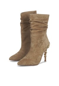 Tan suède enkellaarsjes met een slouchdesign, puntige neuzen en unieke gouden slangenvormige hakaccenten. Gladde textuur en flexibele bovenkant.