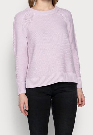 Maglione lavorato a maglia di colore rosa chiaro con polsini e orlo a costine. Presenta un motivo texturizzato e maniche raglan. Abbinato a pantaloni neri.