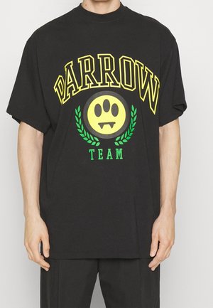 Black cotton T-shirt featuring a large yellow graphic with "DARROW" in bold letters and a smiley face with fangs, framed by green leaves.