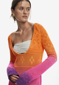 Maglione lavorato a maglia in gradiente da arancione a rosa, con un ampio scollo a barchetta e maniche lunghe aderenti caratterizzate da motivi intricati e una trama aperta.