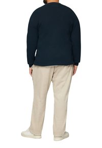 Navy trui met lange mouwen, relaxte pasvorm en ronde hals, gecombineerd met lichtbeige corduroy broek. Witte sneakers maken de outfit af.
