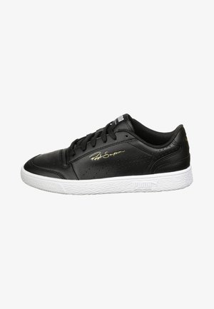 Zapatilla negra de corte bajo con suela blanca, cordones negros, laterales perforados y la firma dorada "Ralph Sampson" en el lateral.