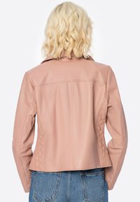 Giubbotto in pelle rosa con un design aderente, caratterizzato da dettagli trapuntati sui lati, colletto a piatto e una texture liscia. Vista posteriore mostrata.
