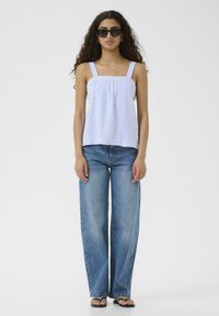 Niebieska i biała w paski koszulka na ramiączkach z kwadratowym dekoltem i regulowanymi ramiączkami, w połączeniu z dżinsami o wysokim stanie i szerokich nogawkach.