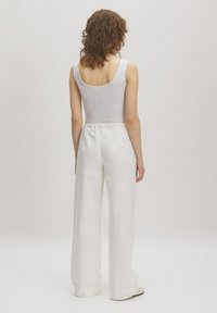 Witte wijde broek met elastische tailleband, gecombineerd met een aansluitend wit tanktop. Zachte stofstructuur, minimalistisch design, geen zichtbare patronen.