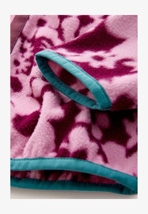 Coperta in pile rosa con motivi astratti viola. Presenta un bordo turchese lungo i bordi. Tessuto morbido, piega che rivela un design stratificato.