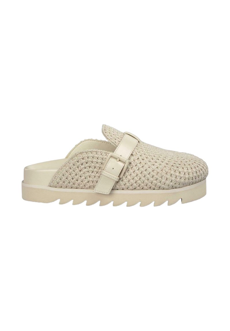 Scarpa slip-on beige intrecciata con un design strutturato in rilievo, una suola piatta di colore chiaro e una cinghia laterale con fibbia per la regolazione.