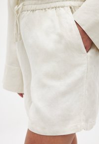 Lichtbeige shorts van gestructureerde stof, met een elastische tailleband, trekkoord detail en zijzakken voor functionaliteit.