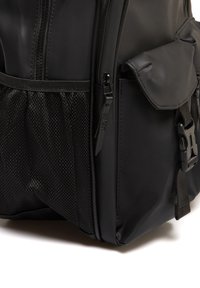 Mochila negra impermeable con un acabado texturizado, que cuenta con un bolsillo lateral de malla, cierre de cremallera y herrajes de correa ajustables.