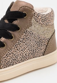 Světlé a černé tenisky vysoké s leopardím potiskem, černými tkaničkami, zlatými akcenty, textura materiálu a měkká vnitřní podšívka.