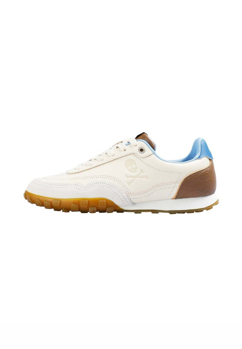 Baskets blanches avec des accents en cuir marron, un col bleu clair, une semelle en caoutchouc texturée et un logo de skull and crossbones sur le côté.