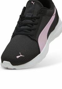 Černá síťovaná atletická obuv s růžovým logem a akcenty, s šněrovacím designem a bílou podrážkou. Texturovaný svršek pro prodyšnost.