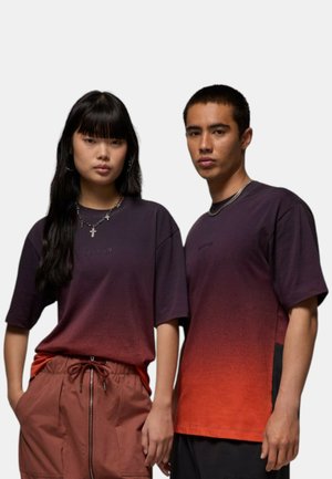 Due persone indossano t-shirt a maniche corte con un gradiente. Le magliette passano da un viola scuro a un arancione brillante. Entrambe presentano un collo rotondo e un marchio discreto.