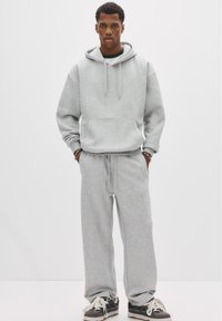 Grå hoodie med framficka och snörning, i kombination med matchande grå sweatpants. Har en avslappnad passform och mjuk textur.