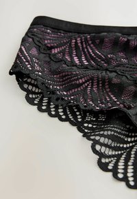 Indumento in pizzo nero con un motivo floreale caratterizzato da accenti rosa, bordi ondulati e una texture morbida.