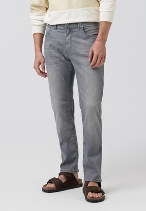 Light gray denim jeans with a slim fit, five-pocket design, and subtle whiskering details, paired with brown sandals.