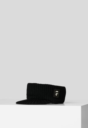 Black ribbed knit visor cap with a small silver emblem featuring a stylized figure on the side.