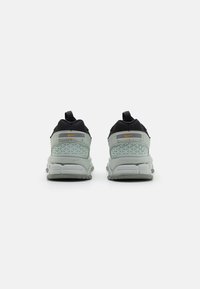 Nike Zoom sneakers featuring a black upper and a light gray patterned heel. Cushioned sole with pull tabs for easy wear.
