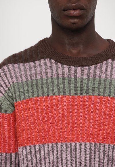 Knit sweater featuring horizontal stripes in red, green, purple, and brown. Ribbed texture with a rounded neckline and short sleeves.