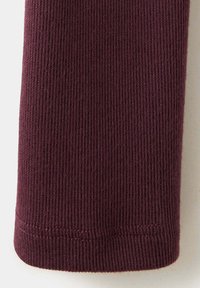 Gros plan sur un tissu tricoté côtelé violet foncé avec un bord plié et cousu.