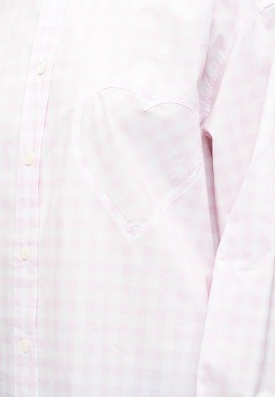 Ροζ ανοιχτό ροζ πουκάμισο με καρό σχέδιο και καρδιά με ραμμένη περίγραμμα στο στήθος, με κουμπιά στο μπροστινό μέρος, μακριά μανίκια ορατά.