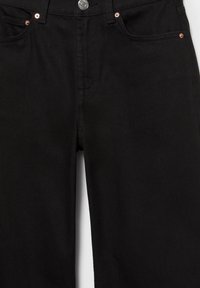 Vue de face d'un jean en denim noir montrant la fermeture par boutons, la braguette zippée, les passants de ceinture et les détails des rivets sur les poches.