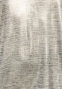Close-up of rough, woven beige fabric with visible texture and subtle pattern variations in a light, neutral tone.