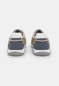 Două adidași cu un superior din pânză bej și accente din denim albastru, având tălpi din cauciuc alb și șireturi bej. Contracția călcâiului întărită.