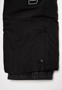 Gros plan sur le poignet d'une veste noire O'Neill avec une doublure intérieure élastique et un poignet extérieur réglable à bouton.