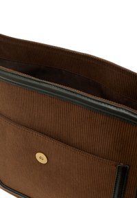 Hnědá kordurová taška uvnitř s černým koženým okrajem, vybavená zlatým patentním uzávěrem a hladkým, podšívkovým kapsou pro organizaci.