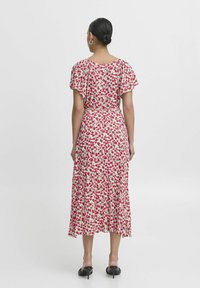 Floral midi dress with flutter sleeves, featuring a pink and green pattern on a cream background. Flowing silhouette and cinched waist.