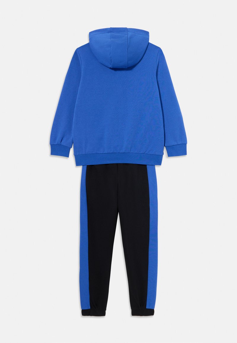 Felpa blu con tasca a marsupio e pantaloni della tuta neri con pannelli laterali blu. Realizzati in un tessuto morbido con polsini e vita a coste.