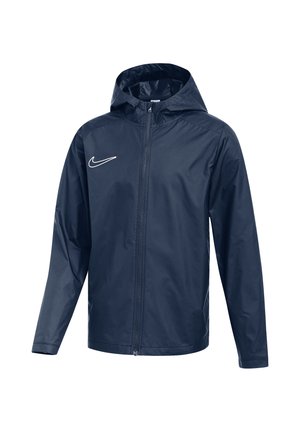 Giacca impermeabile blu scuro con cappuccio, zip frontale completa e piccolo logo bianco Nike sul petto sinistro.