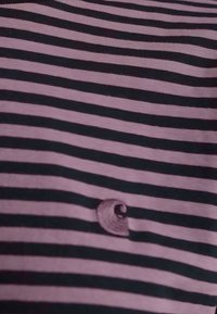 T-shirt a righe realizzato in morbido cotone, con righe orizzontali alternate in rosa e nero. Dettaglio del piccolo logo nell'angolo in basso a sinistra.