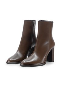 Stivali alla caviglia in pelle marrone con un design elegante, punta affusolata e tacco alto a blocco. Presentano una zip laterale per una facile vestibilità.