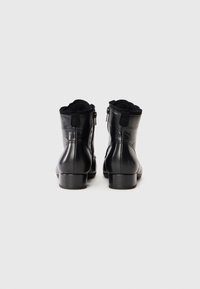 Black leather ankle boots with a smooth finish, round toe, small block heel, dual side zippers, and scalloped edge at the top.