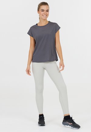 Gråstribet t-shirt med korte ærmer, parret med lys grå leggings og sorte træningssko. Har en afslappet pasform og en uformel stil.