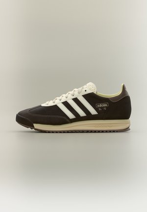 Baskets Adidas SL '72 en noir et blanc avec semelle crème, trois bandes blanches et fermeture à lacets, vues de côté sur fond neutre.