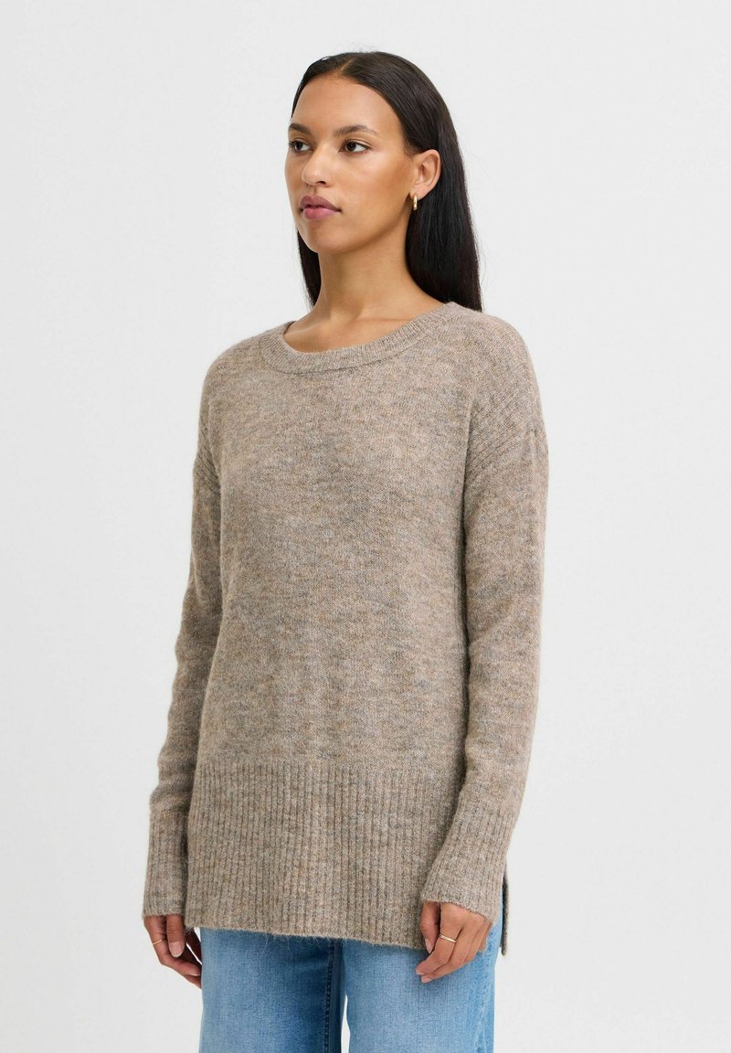 Pull en tricot beige avec un col rond, des manches longues, un ourlet côtelé et des fentes sur les côtés. Fabriqué à partir d'un matériau doux et texturé.