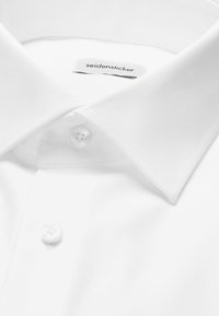 Col de chemise blanche avec boutons, avec une étiquette visible indiquant "seidensticker."